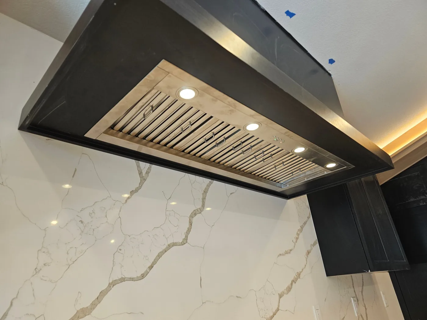 Custom stainless steel range hood installed over a marble backsplash in a Vancouver, WA kitchen