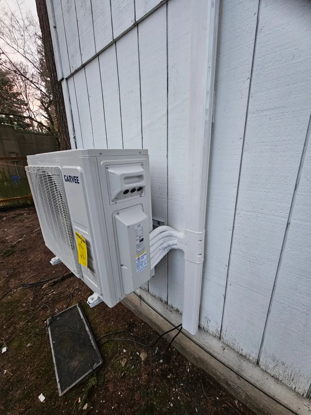 Side-angle view of a wall-mounted mini-split heat pump condenser installation in Vancouver, WA